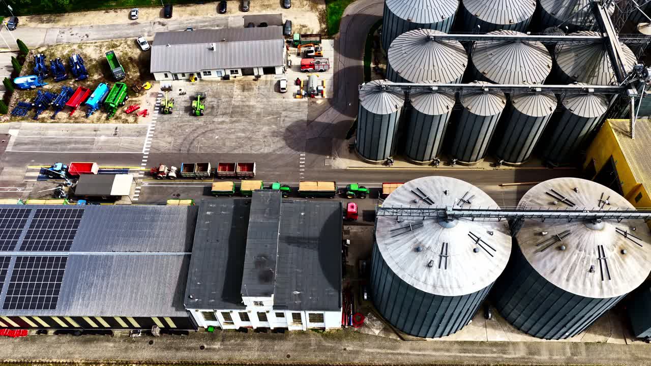 Luftaufnahme eines Industriekomplexes mit Silos und Solarmodulen.