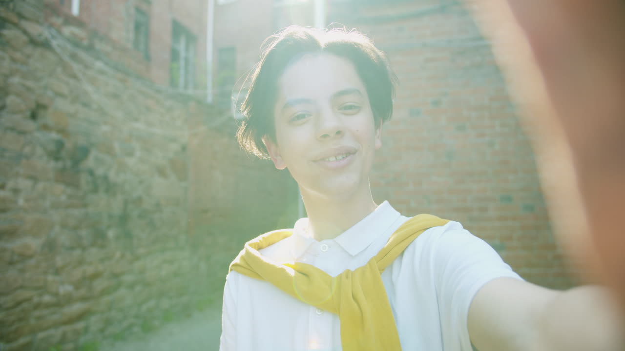 Smiling young adult taking a selfie in a city alley