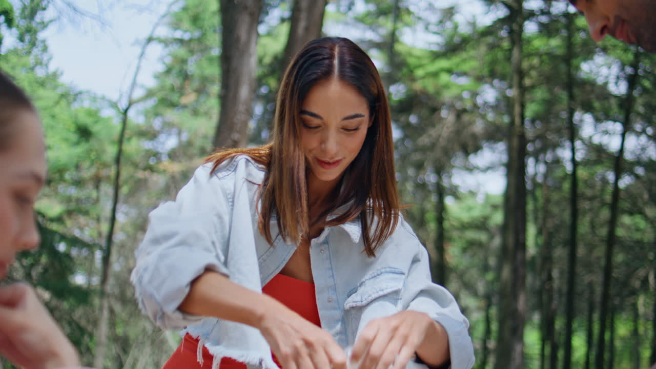 Smiling woman salting food at picnic in forest closeup. Happy girl with friends