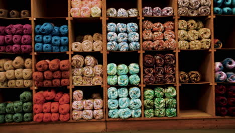 shelves displaying various colors of yarn in fabric factory store, dolly in