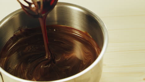 close up of melted chocolate mixing with whisk in slow motion