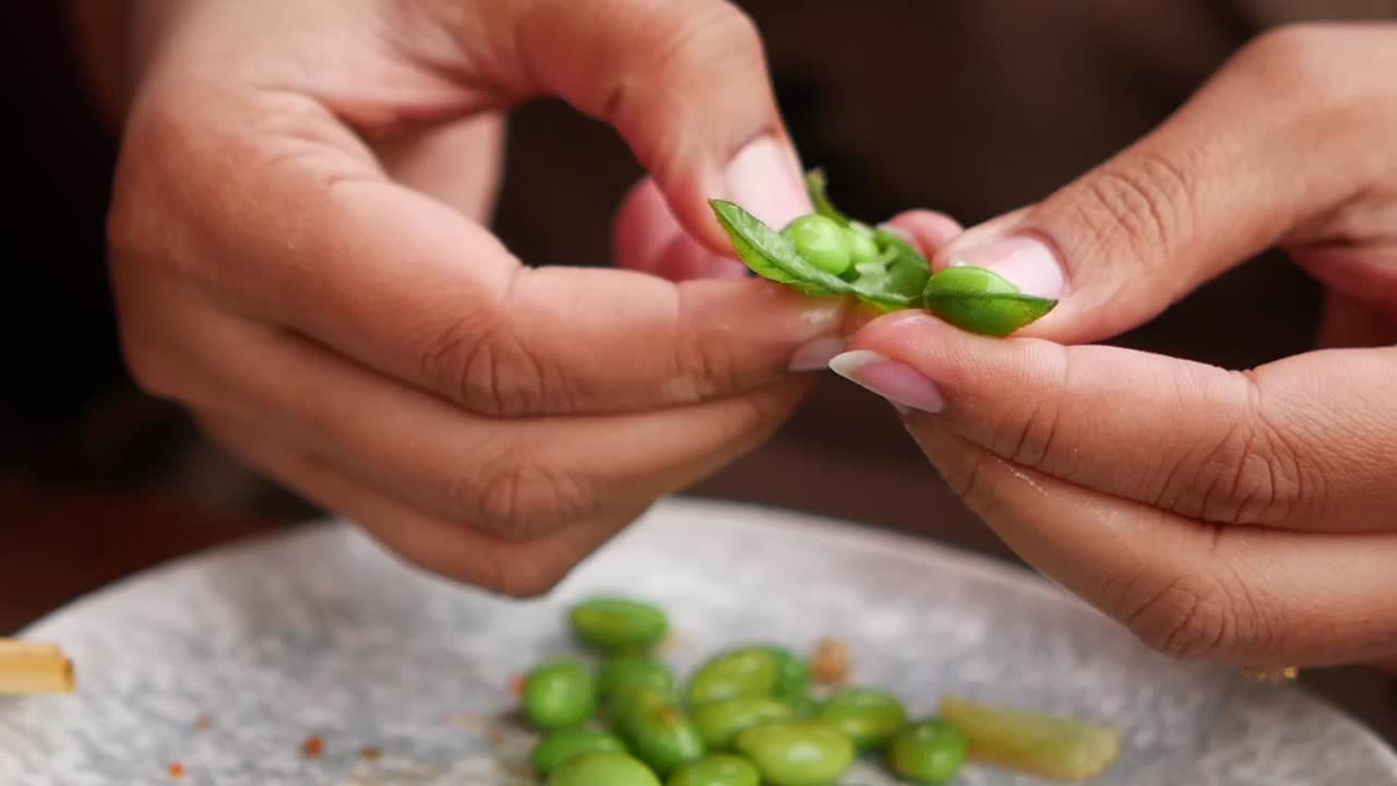 Mani che sgusciano edamame