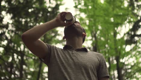 caucasian man drinking coffe from paper cup in forest, low angle view middle shot