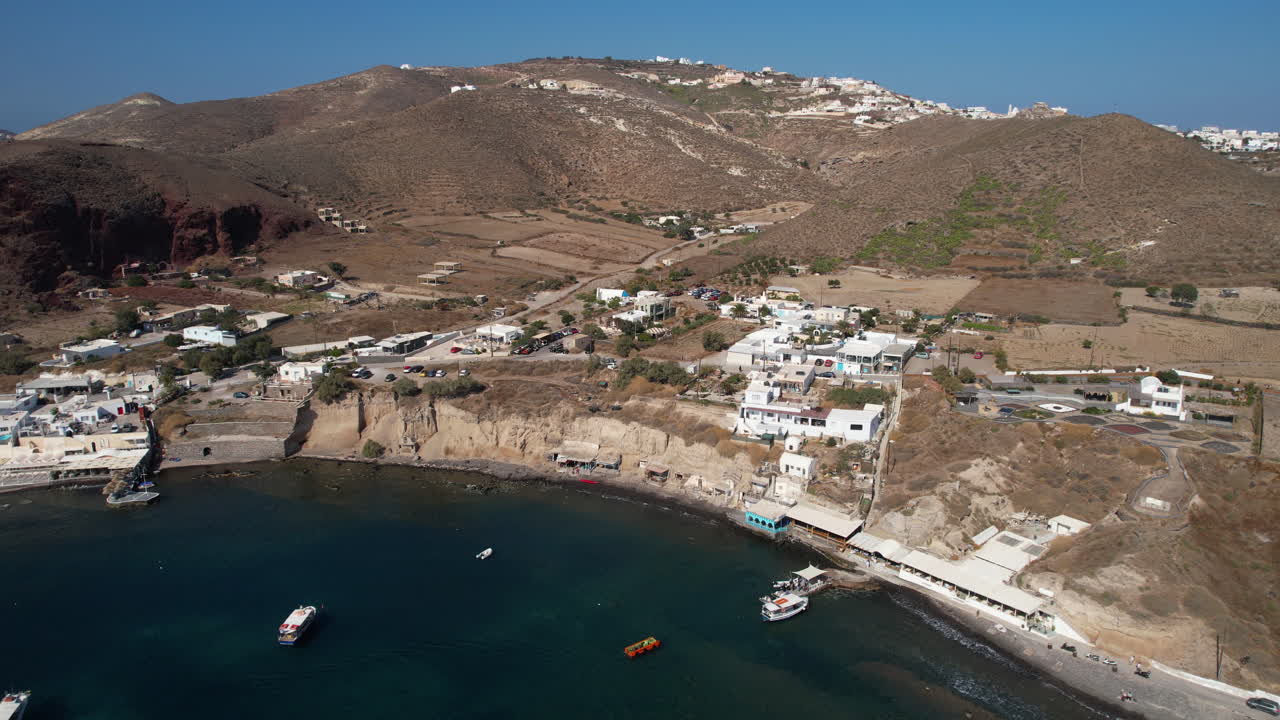 vista aérea de un idílico pueblo en la costa sur de la isla de santorini, grecia, edificios, paisajes y barcos