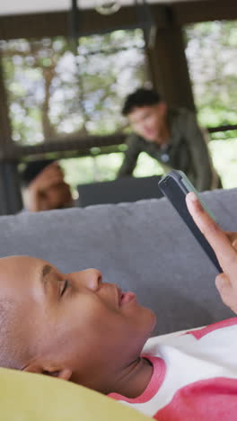 vertical video of happy diverse male teenage friends using smartphone