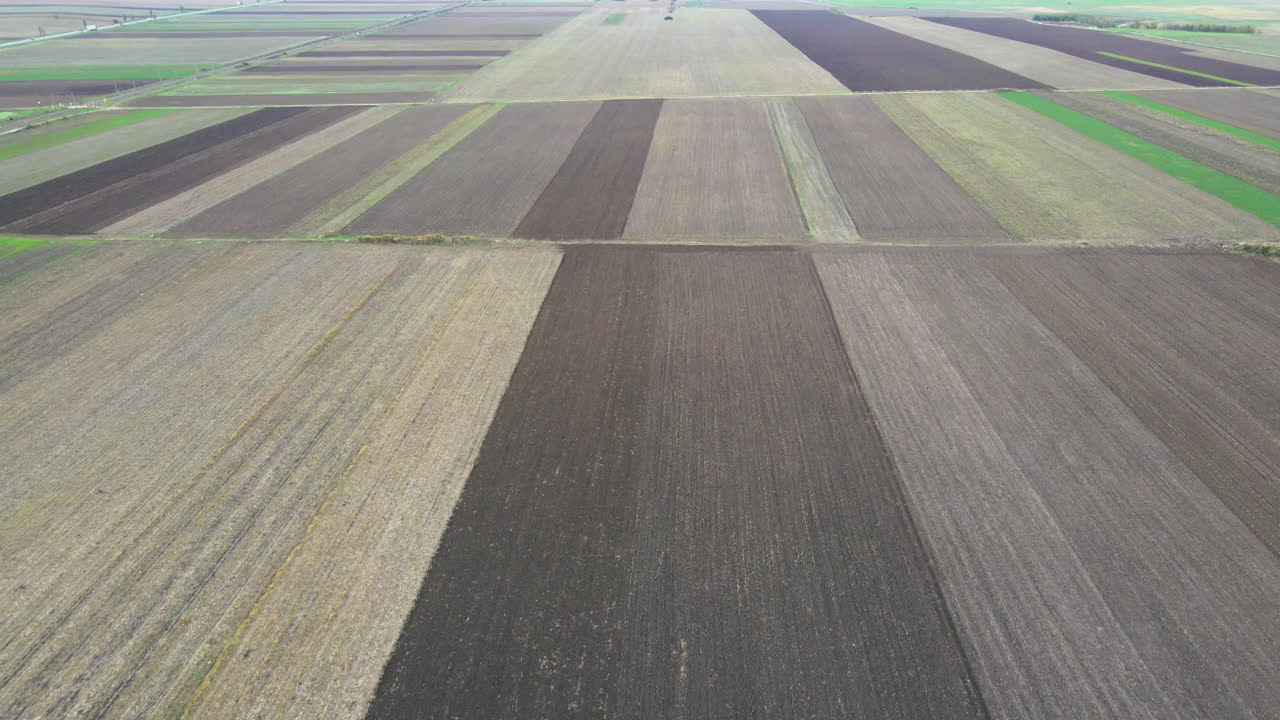 Bare brown dead farmland in the cold winter drone aerial pan up to grey sky