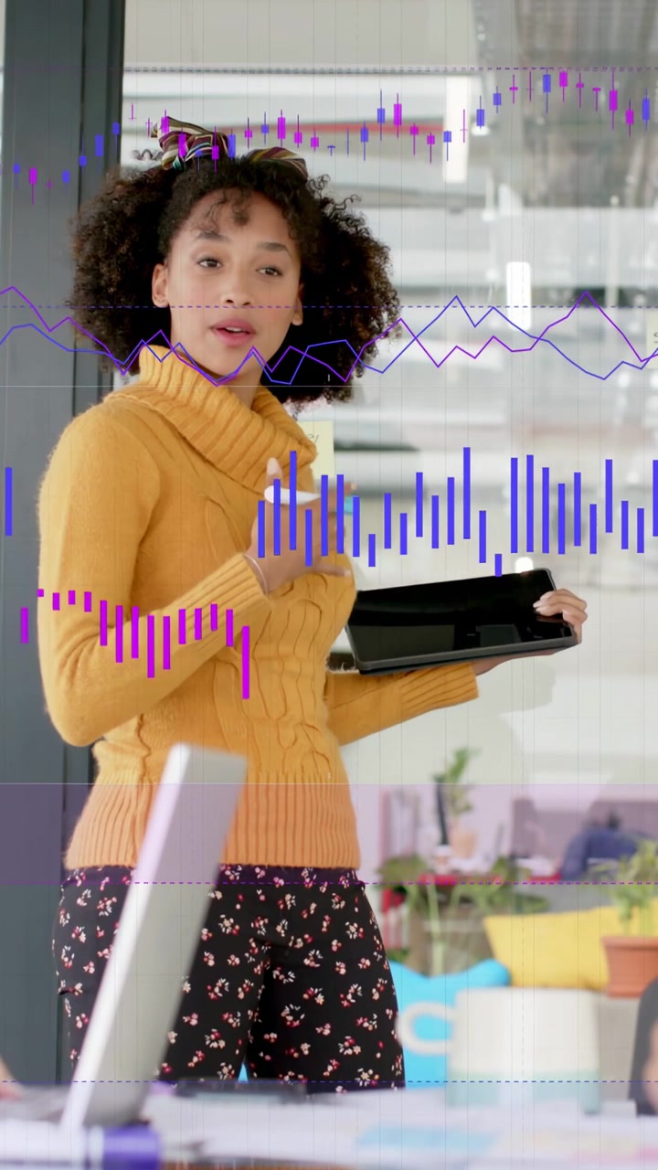 Vertical video: Starting woman in mustard top presenting data at office, holding tablet stylus