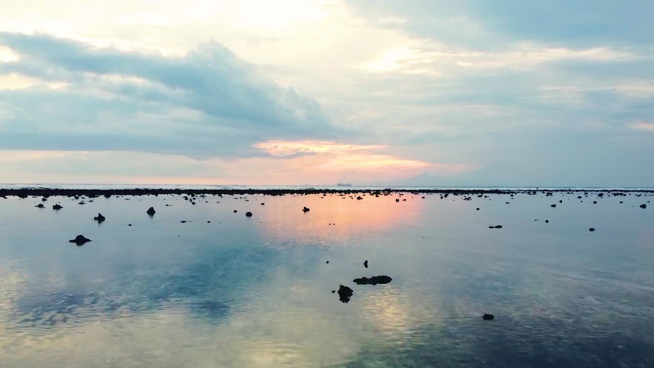 해변의 잔잔한 후미에서 흐리고 화려한 하늘의 마법 같은 반사