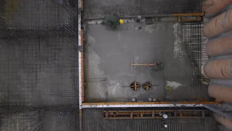 Top-down-aerial-view-of-construction-workers-laying-wet-cement,-Israel