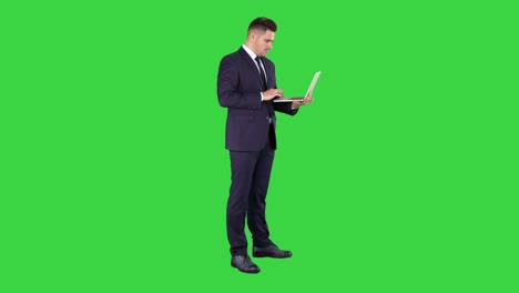businessman standing and using laptop on a green screen, chroma key