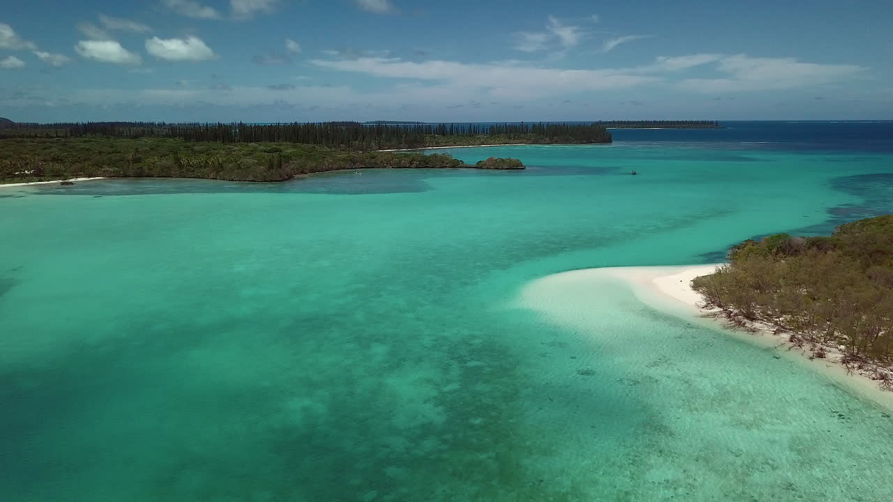 Green forest and aqua ocean. New Caledonia archipelago. Forward dolly.