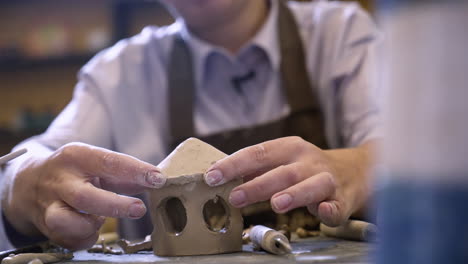 woman sculpting a small clay house