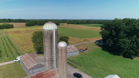 silos de grano en órbita aérea en una granja rural con campos de cultivo en el fondo, 4k