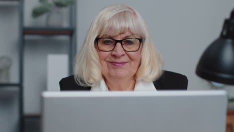 Senior-businesswoman-wears-glasses-working-at-home-office,-online-webinar-using-laptop-computer