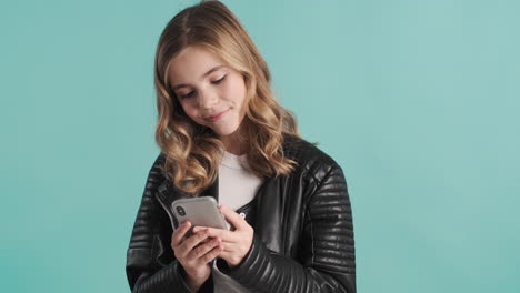 teenage caucasian girl in leather jacket using her smartphone.