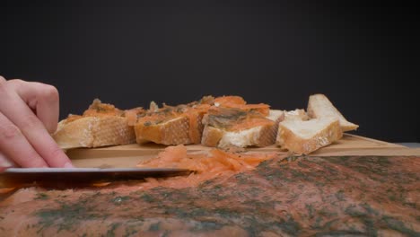 slider view of woman cutting raw salmon into pieces and putting them on the homemade bread