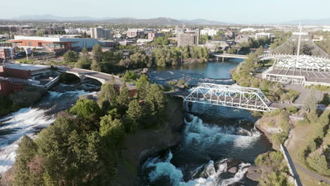 downtown spokane sits at the edge of the river, with waterfalls and bridges in view. the city blends with nature all around