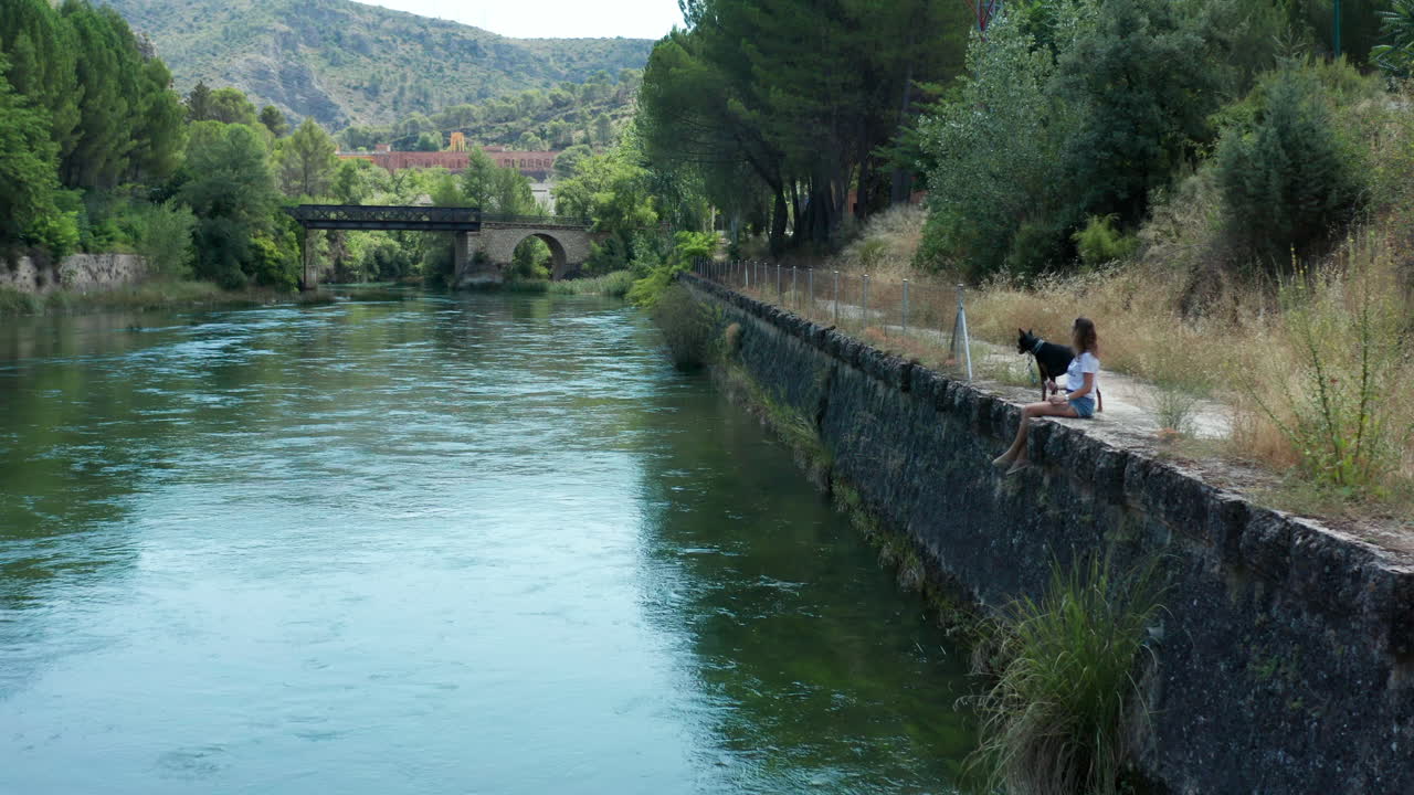 Young girl walking her dog along the riverbank. People and pets concept
