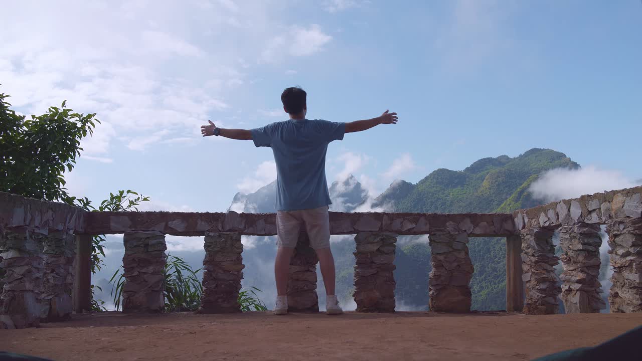 베란다 절벽 위에 서서 손을 들고 축하하는 아시아 하이커 남성, 안개 산의 꼭대기에 도달합니다.