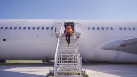 a traveler or backpacker man going up on passenger stair with boarding ramp steps. commercial airplane, aircraft with blue sky background in travel trip and transportation concept. flying vehicle.