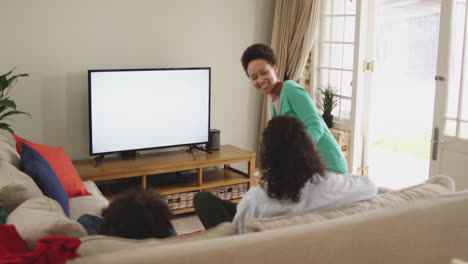 Una-Pareja-De-Lesbianas-De-Raza-Mixta-Y-Su-Hija-Viendo-La-Televisión-Sentada-En-El-Sofá