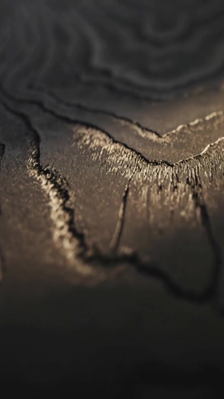 Vertical video: Moving camera and light revealing texture on charred surface with ridges in studio