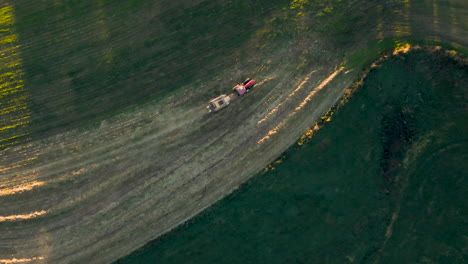 top-down aerial of tractor pulling baling machine in late afternoon light in rural pennsylvania, u