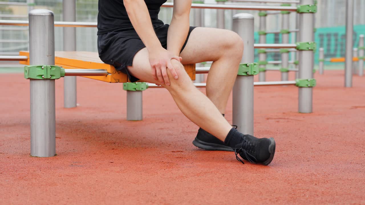 Fixed shot of young man exercising knee and ankle movements while seated outdoors