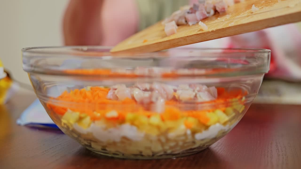 Slow motion close up of traditional salad prep with herring topping stage