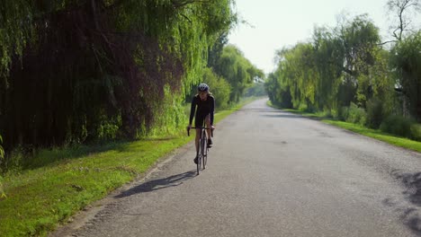 male cyclist in helmet rides bicycle along the track by rular place