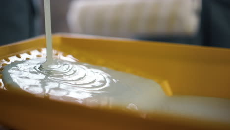 white paint spreading in yellow tray for paint roller on blurred background.