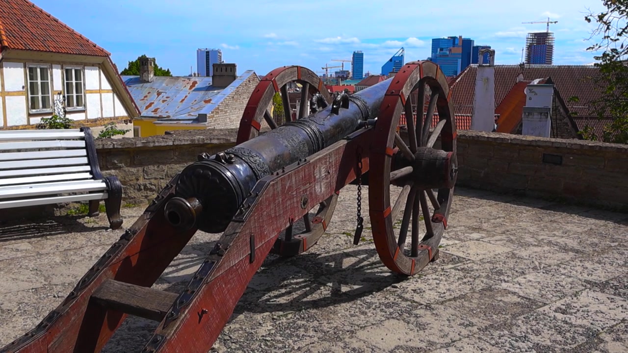 Estonya'nın Tallinn şehrinin tarihi merkezine bakan bir tahkimat duvarındaki eski ortaçağ topu Roter Lowe, arka plandaki modern şehir manzarasıyla antik tarihi harmanlıyor.