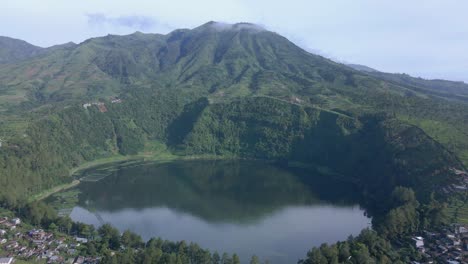 Aerial-view-of-beautiful-lake-surrounded-by-hill-and-forest-in-the-morning