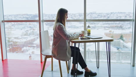 confident happy woman sitting at table and having tea. beautiful woman enjoying lunch break time at work. side view.