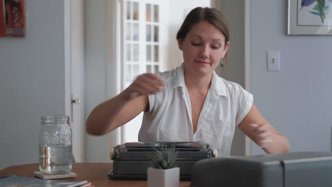 Wide shot caucasian woman loading paper into typewriter