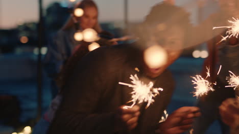 cheerful group of friends holding sparklers celebrating new years eve on rooftop at night having fun dancing enjoying holiday party celebration diverse young people waving festive fireworks