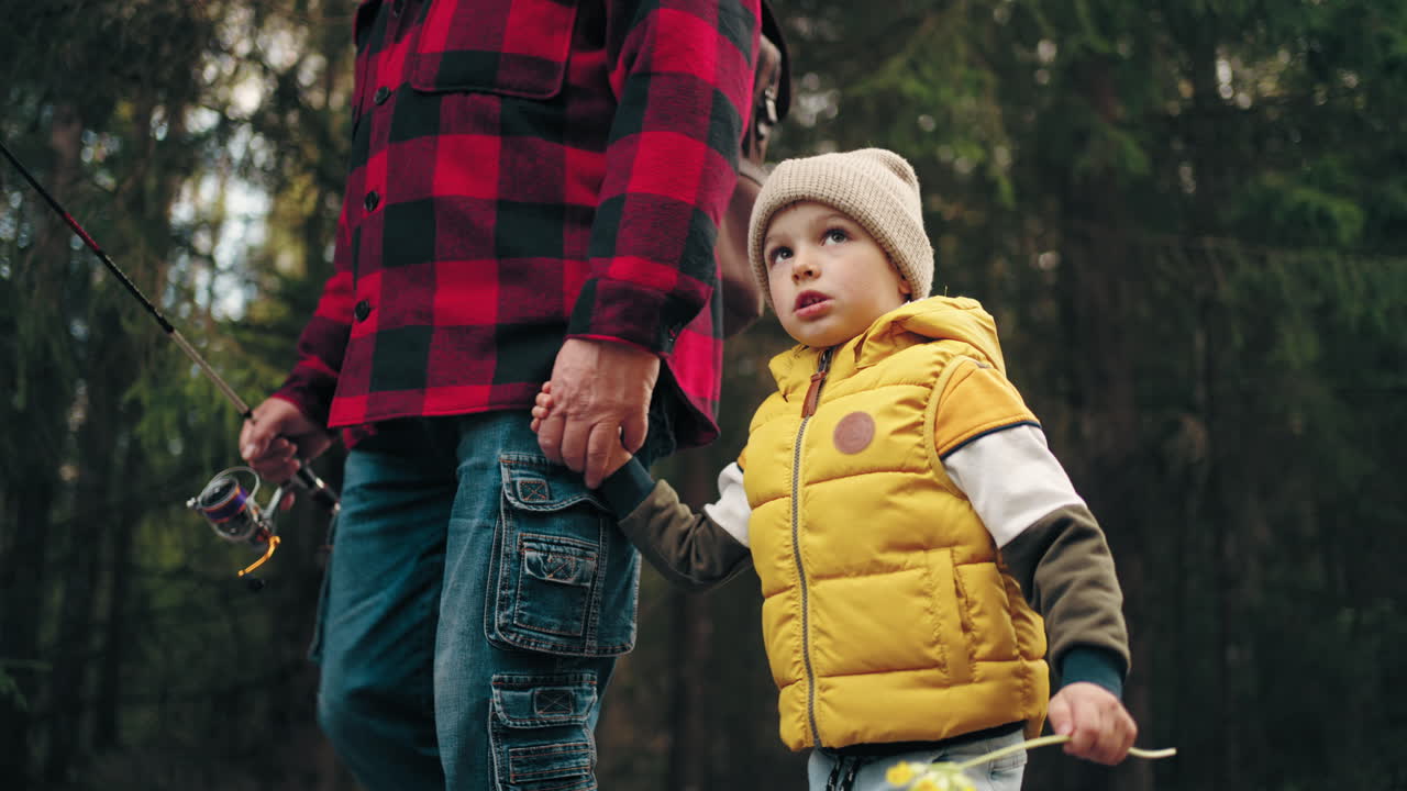 niño divertido está caminando en la naturaleza y sosteniendo la mano de su padre o abuelo infancia feliz