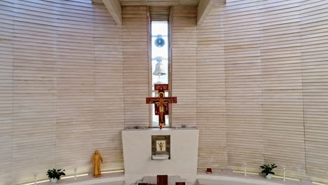 Bells-ringing-in-modern-church-behind-the-altar-with-cross---interior-aerial-shot