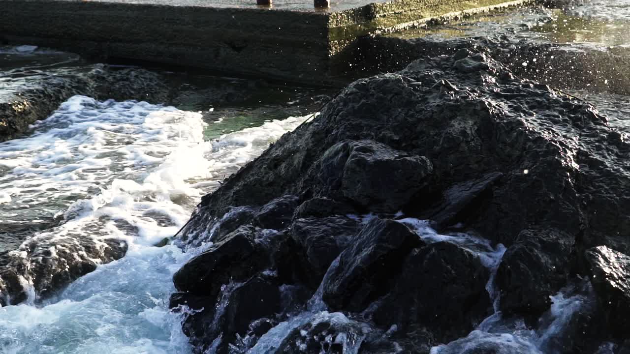 Rock seaside shore. Close up view of waves in sea smashing against rocks