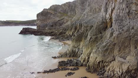 descending aerial drone shot with unusual coastal rock formation and gentle sea waves 4k