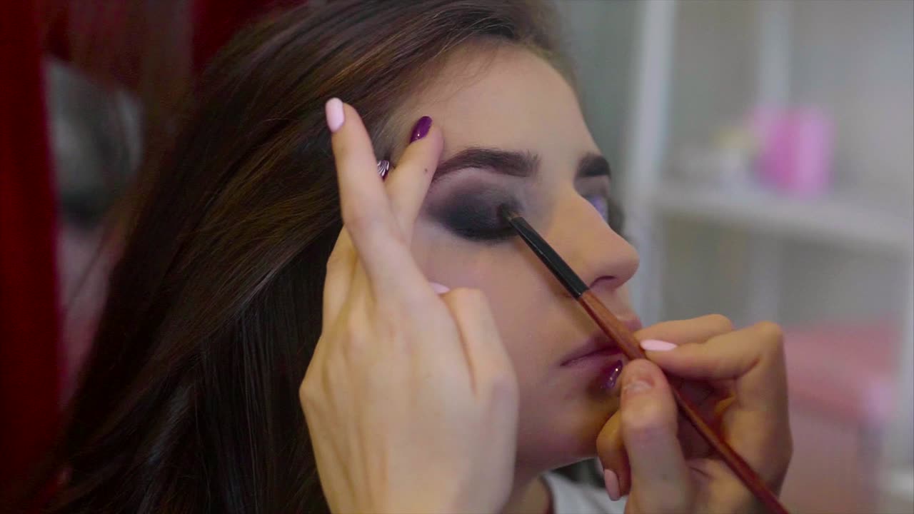 artista de maquillaje aplicando sombra de ojos