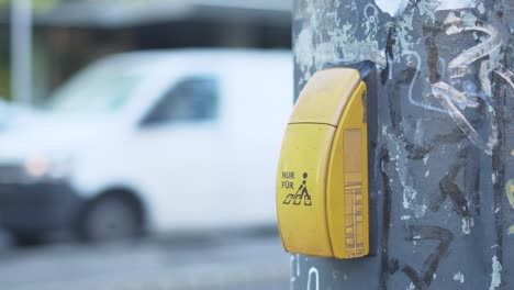 botón de señal amarilla para peatones ciegos en viena con coches en el fondo