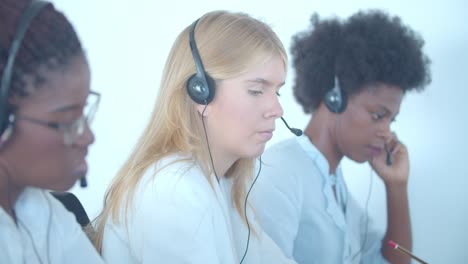 row of diverse female call center operators in headset taking calls