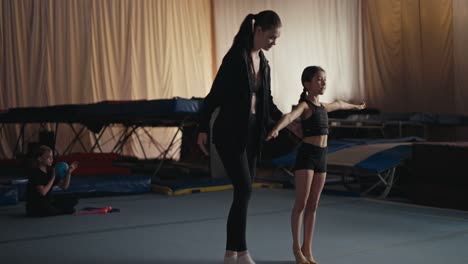 young girl trains gymnastics in a gym with her coach