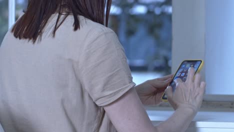 woman engrossed in her smartphone scrolls upwards, eyes focused screen