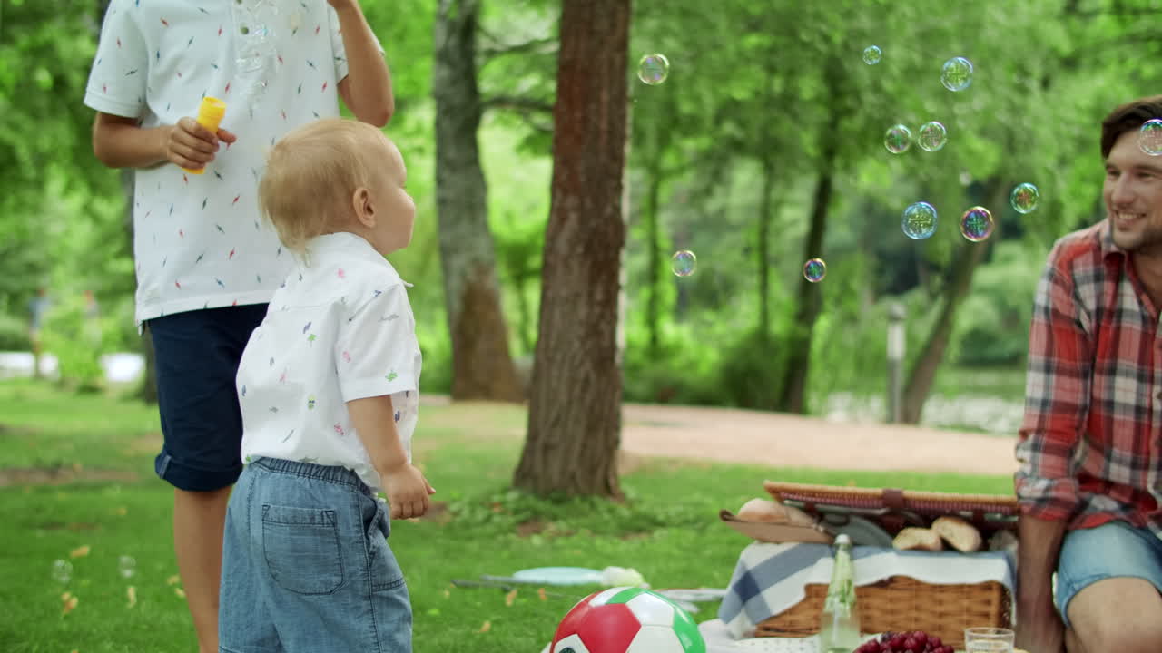 padre sonriente mirando a los niños en el parque. familia pasando el fin de semana juntos