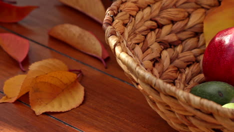 Close-up-of-ripe-red-pomegranates-in-wicker-basket-on-table-in-garden-with-green-fruit