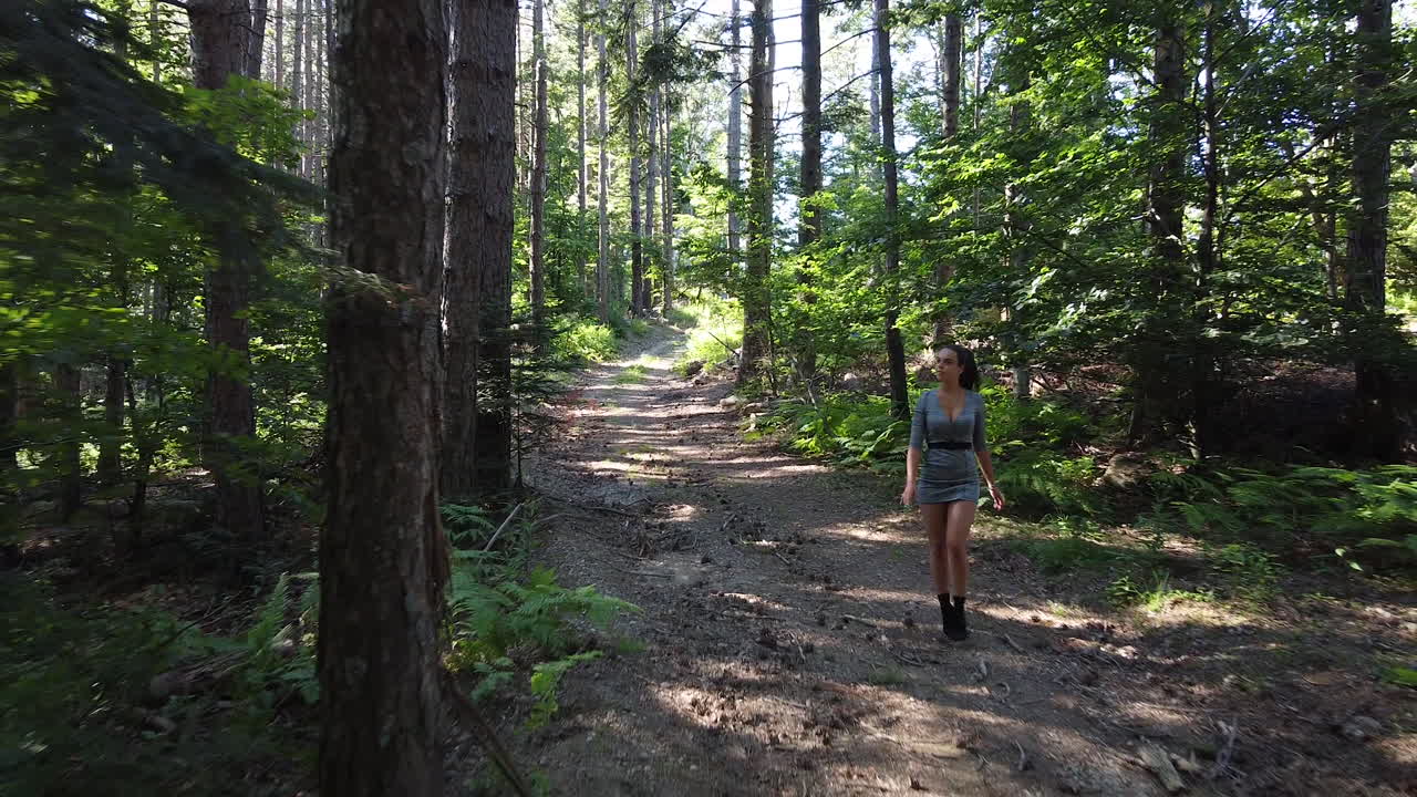 joven caucásica saludable caminando relajada dentro de un bosque mágico en un día soleado, a principios de verano