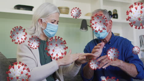 animación de células virales con una pareja caucásica mayor con máscaras faciales desinfectando las manos