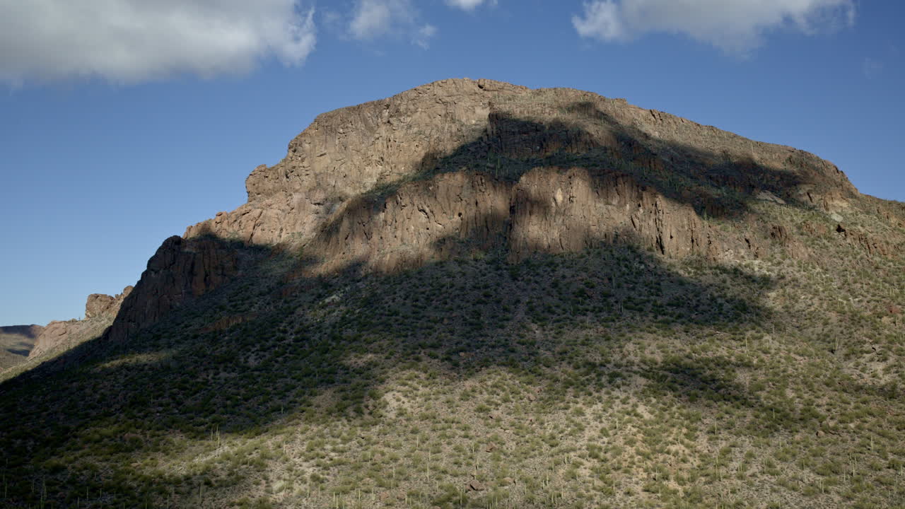 drone disparado volando hacia la montaña del desierto cubierto de cactus con sombras de nubes moviéndose a través del paisaje